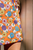 Orange 1960's style mini dress with multi-color floral print. Print by Dave Hill.