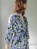 Woman wearing a black robe with a purple flower print. Print by Dave Hill.